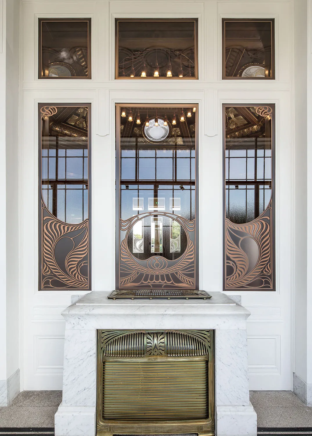 Art nouveau-interieur met decoratieve glas-in-loodramen, een marmeren open haard en een messing kachel