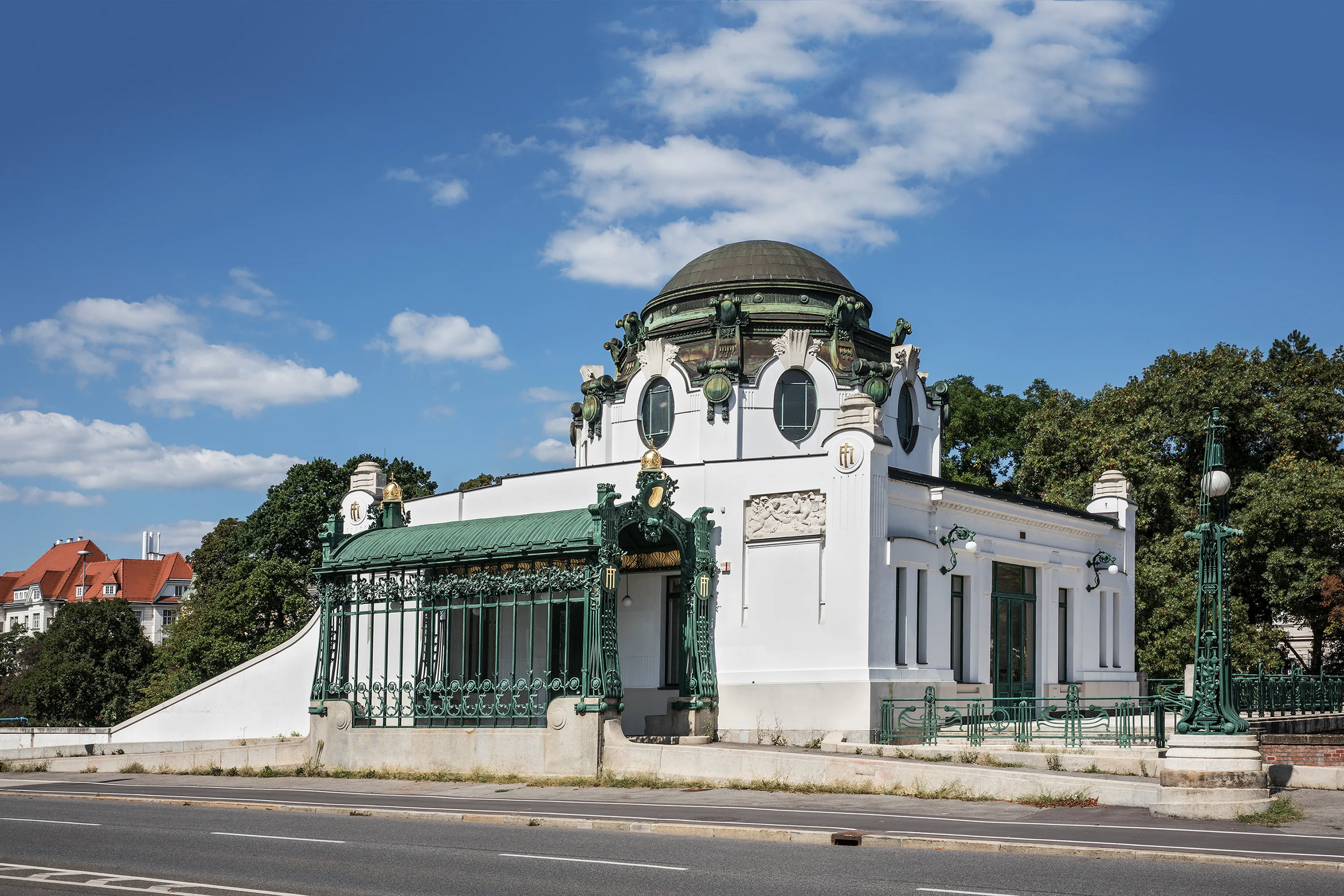 White Art Nouveau pavilion with green metal railings and a dome under a blue sky