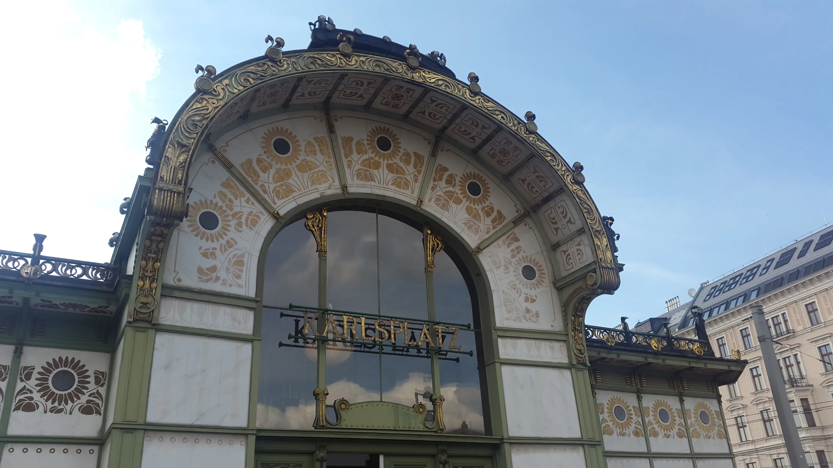 Art Nouveau pavilion with ornate gold detailing and a large arched window displaying the word 'KARLSPLATZ'