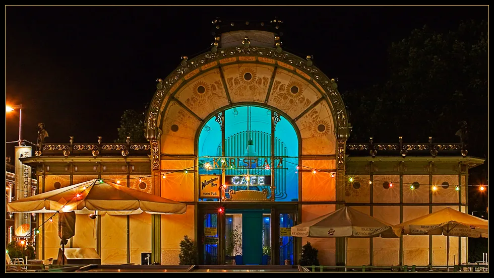 Pabellón Art Nouveau de noche con entrada arqueada azul iluminada y fachada decorativa