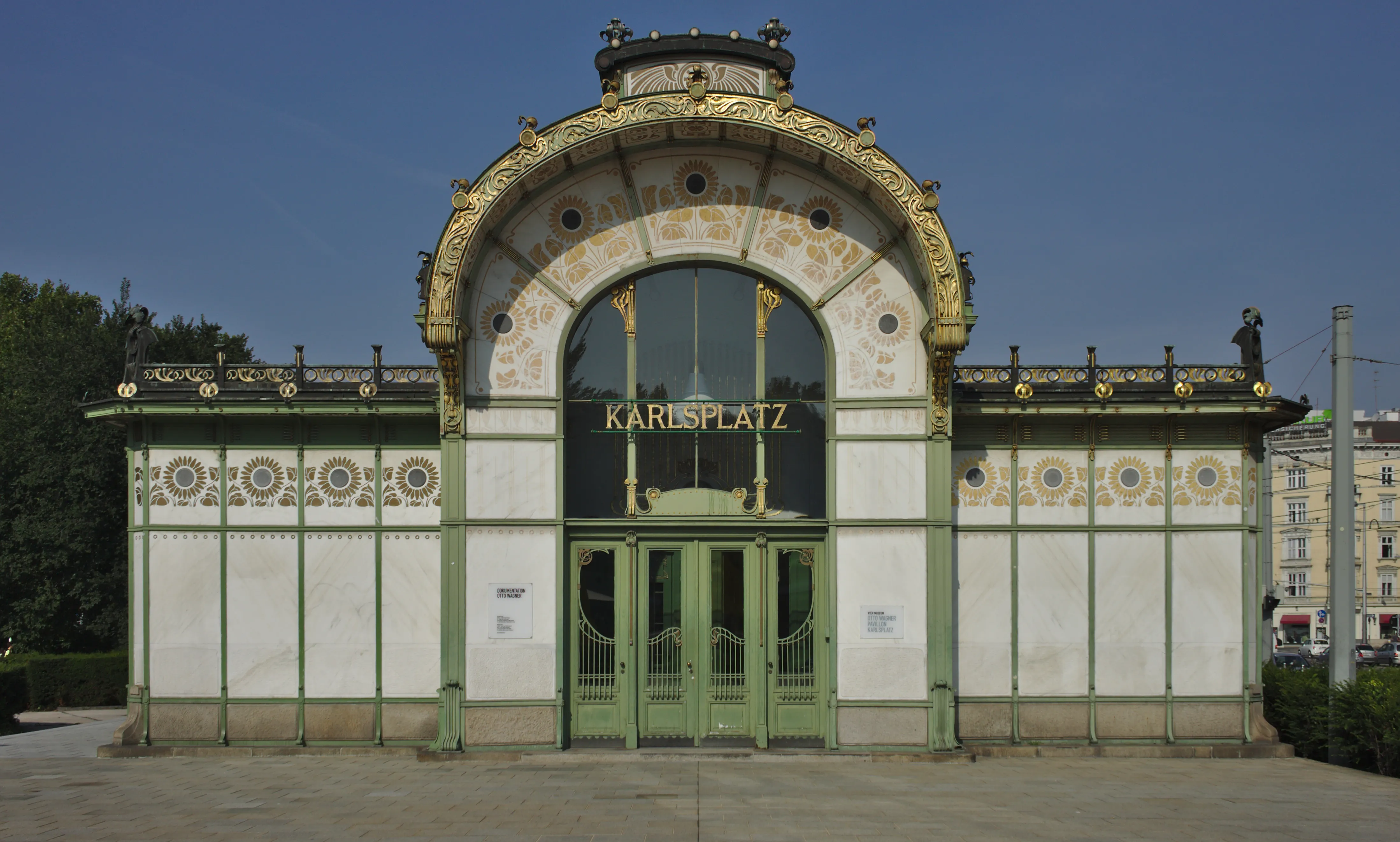 Art Nouveau pavilion with arched entrance, gold and green detailing, and 'KARLSPLATZ' sign