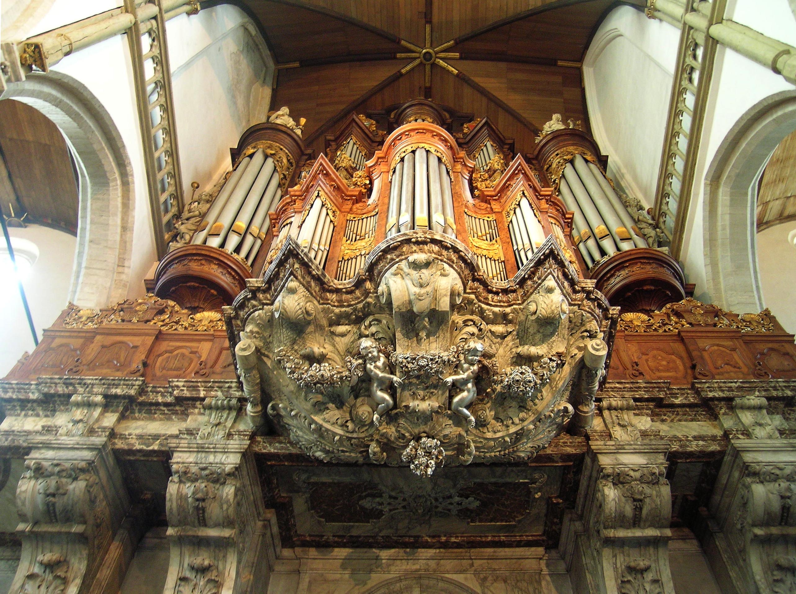 Ornate pipe organ with detailed carvings and golden pipes inside a historic church