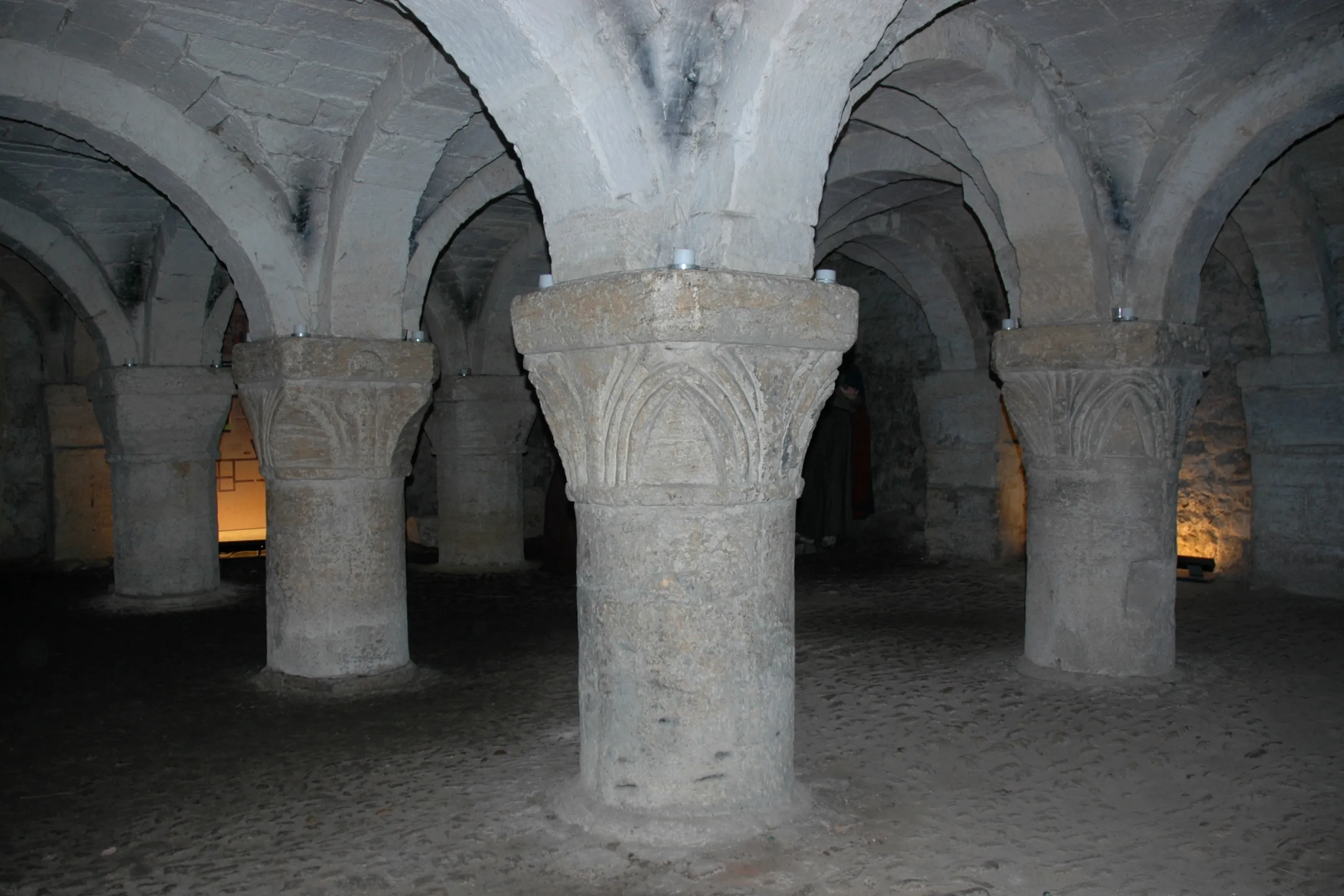 Columnas de piedra con capiteles tallados que sostienen bóvedas de arco en el interior de una cripta medieval