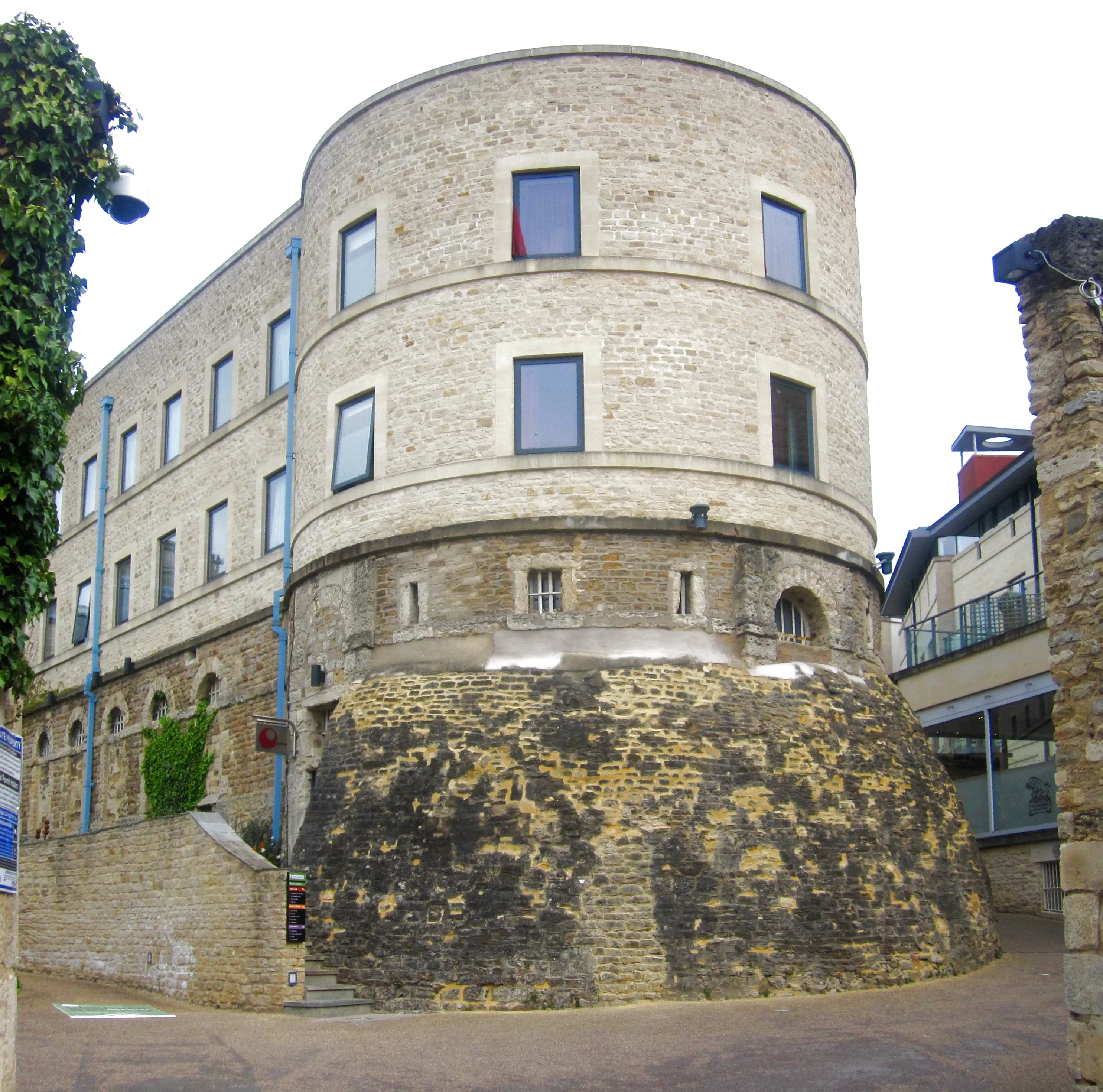 Torre redonda de piedra del Oxford Castle con edificio rectangular adosado, que presenta ventanas arqueadas y una base de ladrillo desgastado