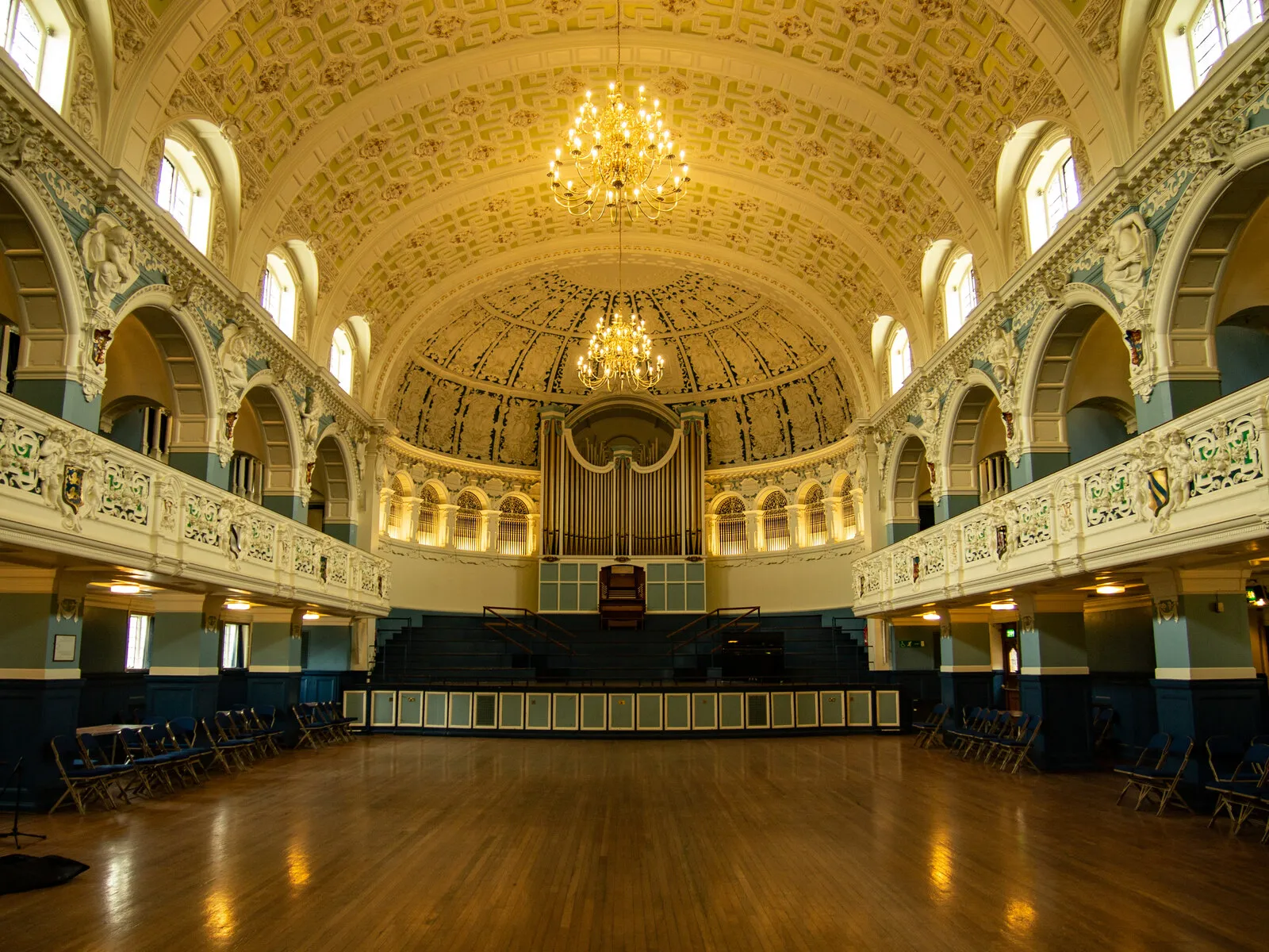 Wspaniałe wnętrze głównej sali Oxford Town Hall z ozdobnym sklepieniem kolebkowym, bliźniaczymi żyrandolami, dużymi organami piszczałkowymi, łukowatymi oknami i polerowaną drewnianą podłogą