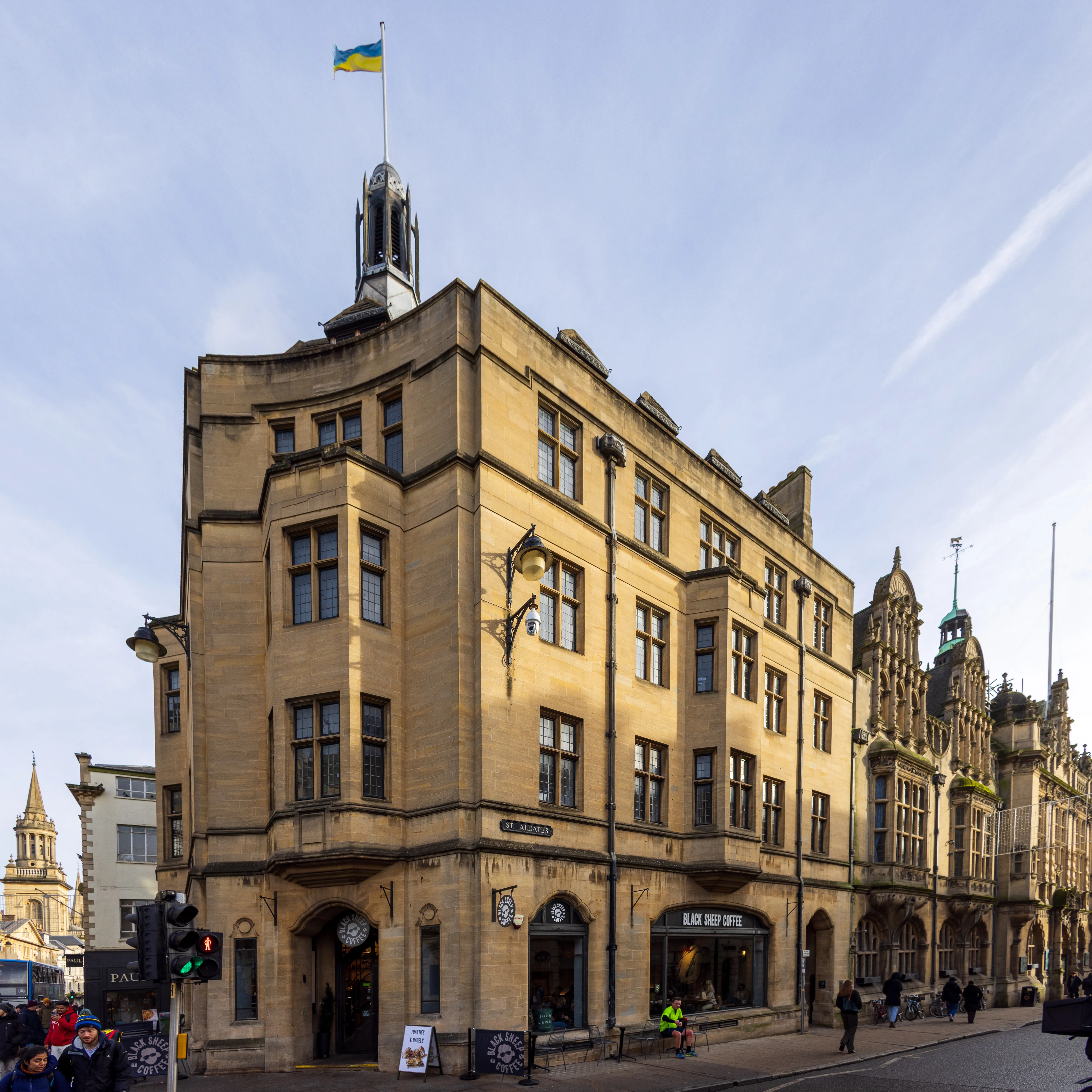 Kamienny budynek użyteczności publicznej na rogu ulicy z ukraińską flagą powiewającą na kopule na dachu, Oxford High Street