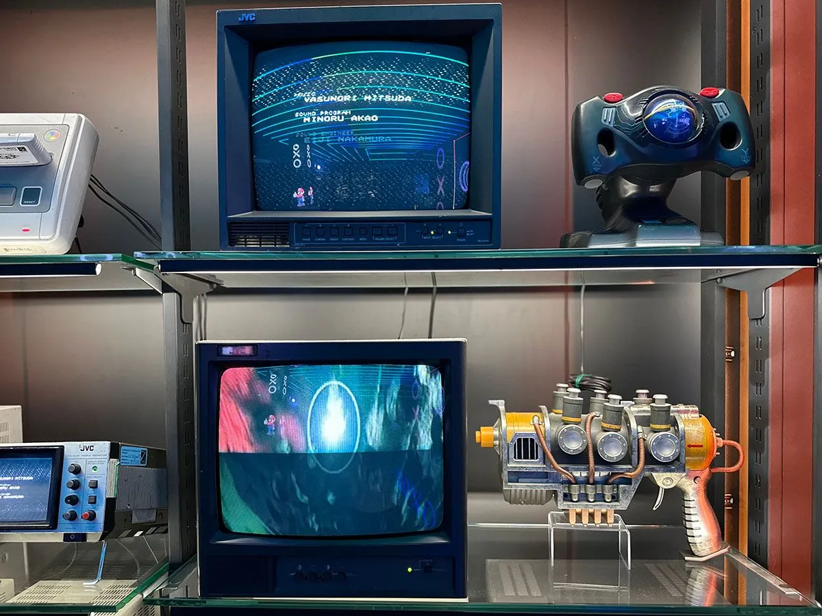 vintage arcade machines and gaming equipment on display in a glass case
