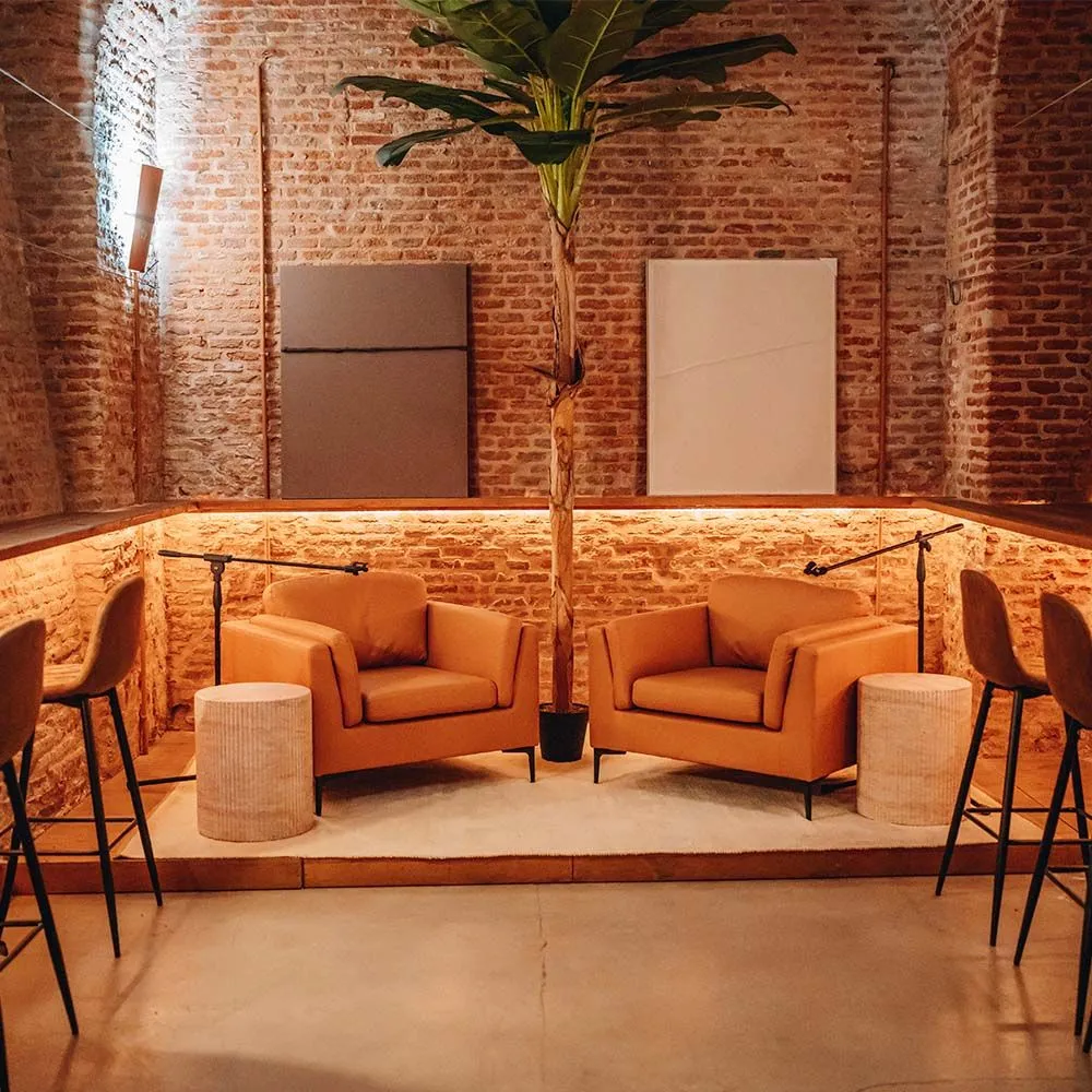 oranje fauteuils en een hoge plant in een lounge met bakstenen muren