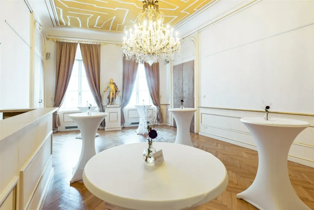 Barokke interieurkamer met gouden plafond, kroonluchter en witte tafels