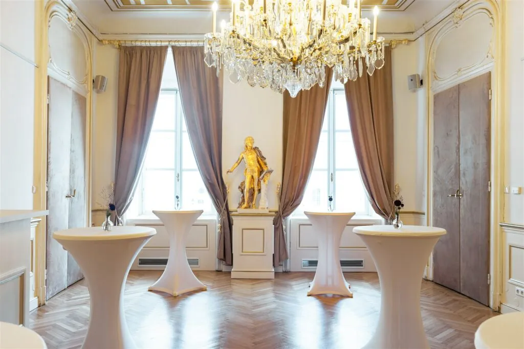 Barok interieur met een kroonluchter, gouden beeld en hoge ramen met bruine gordijnen