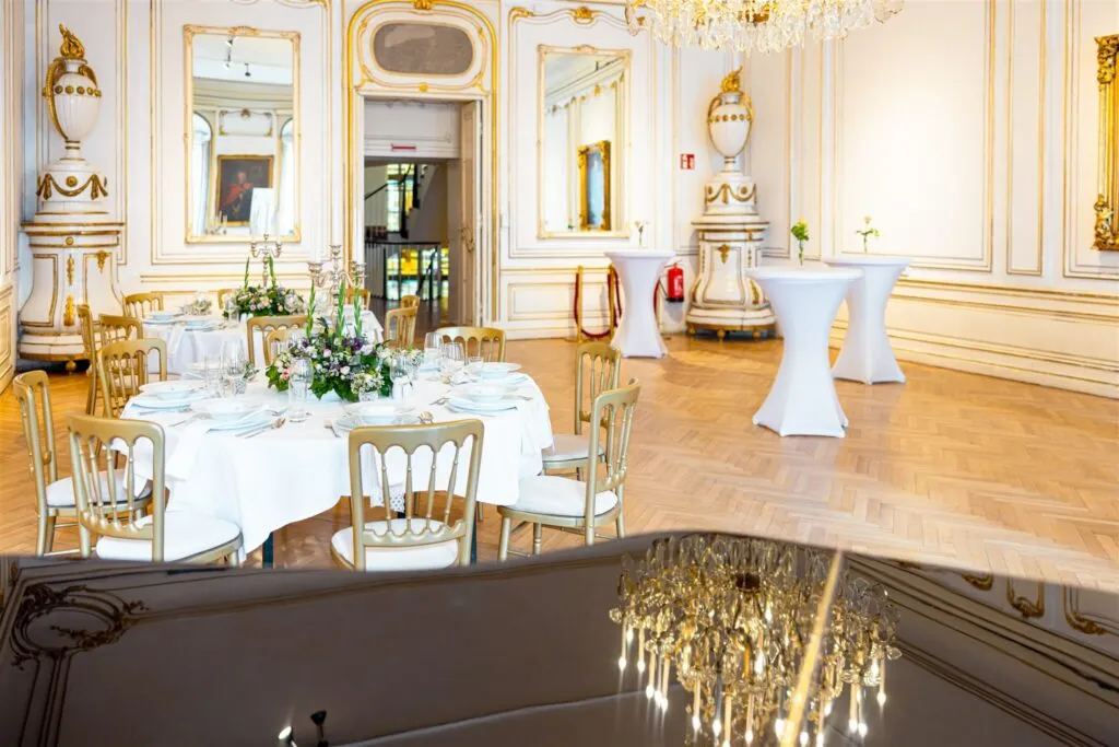 Barok interieur met sierlijke witte muren, vergulde decoraties, een kroonluchter en een gedekte eettafel