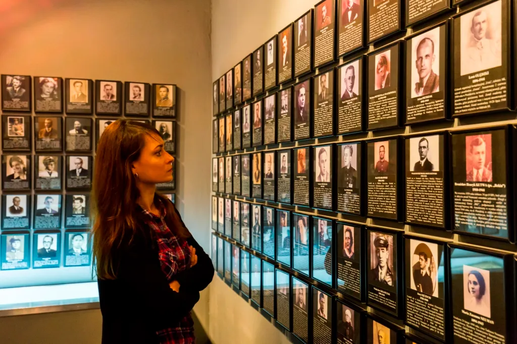 A woman looking at a wall of framed portraits and biographical plaques in a museum gallery