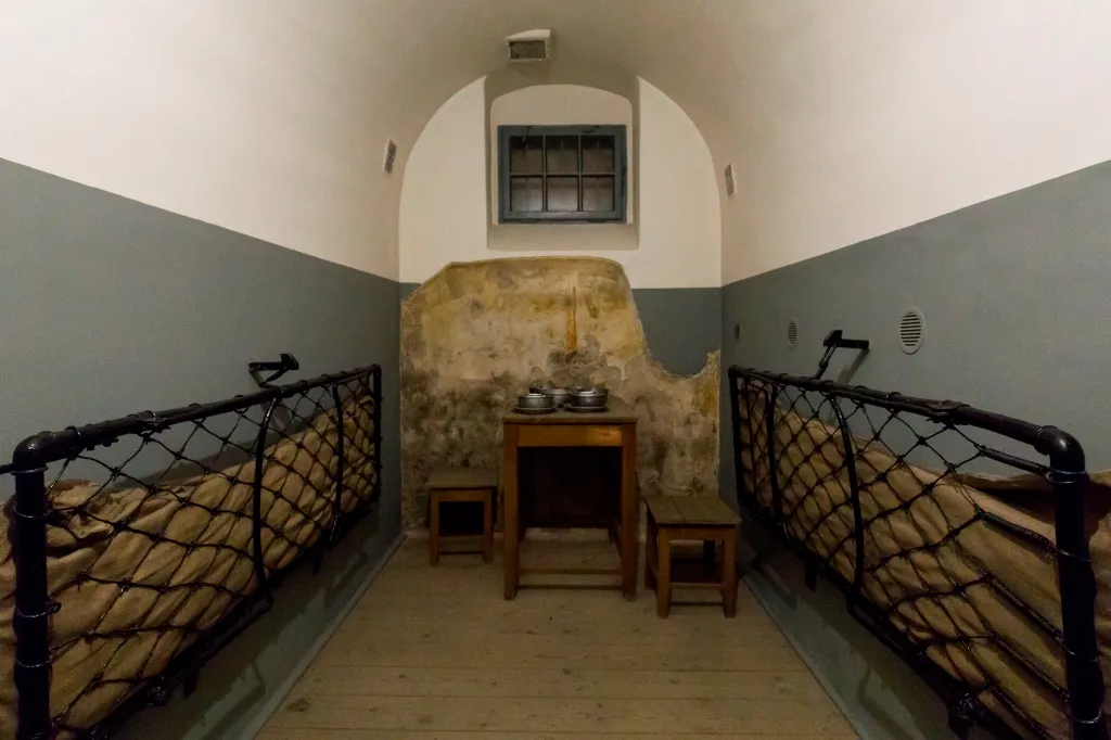 prison cell with bunk beds, table, and barred window