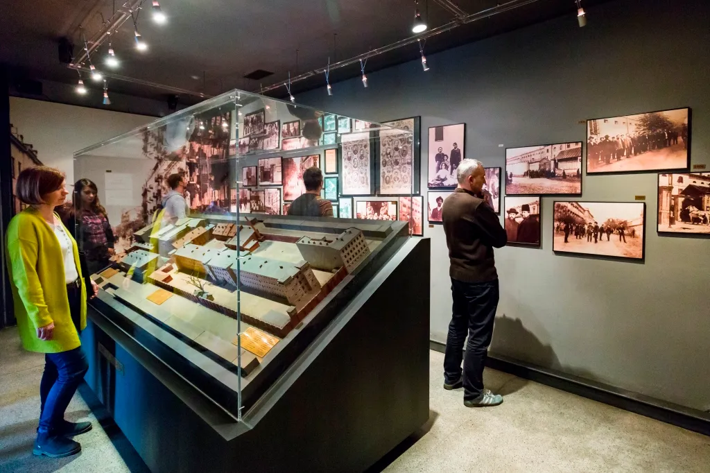 Interior of Pawiak Prison Museum with a glass-enclosed model of the prison and visitors viewing historical photographs on the wall