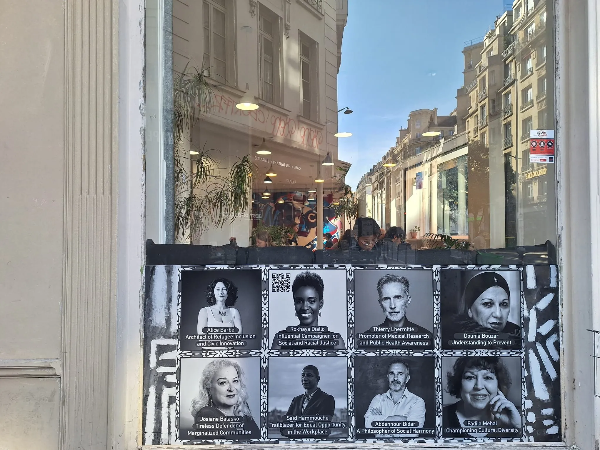 Vitrineweergegeven met een raster van zwart-witportretten van diverse personen, met de naam Peace Museum Vienna zichtbaar onderaan.