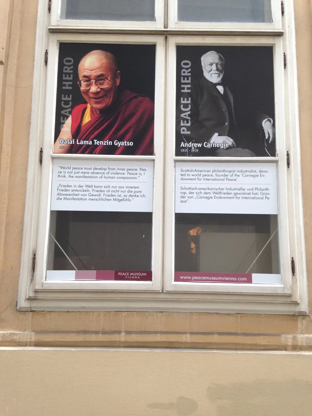 Wystawa sklepowa z plakatami Dalajlamy i Andrew Carnegie z etykietą 'Bohater Pokoju' w Wiedeńskim Muzeum Pokoju
