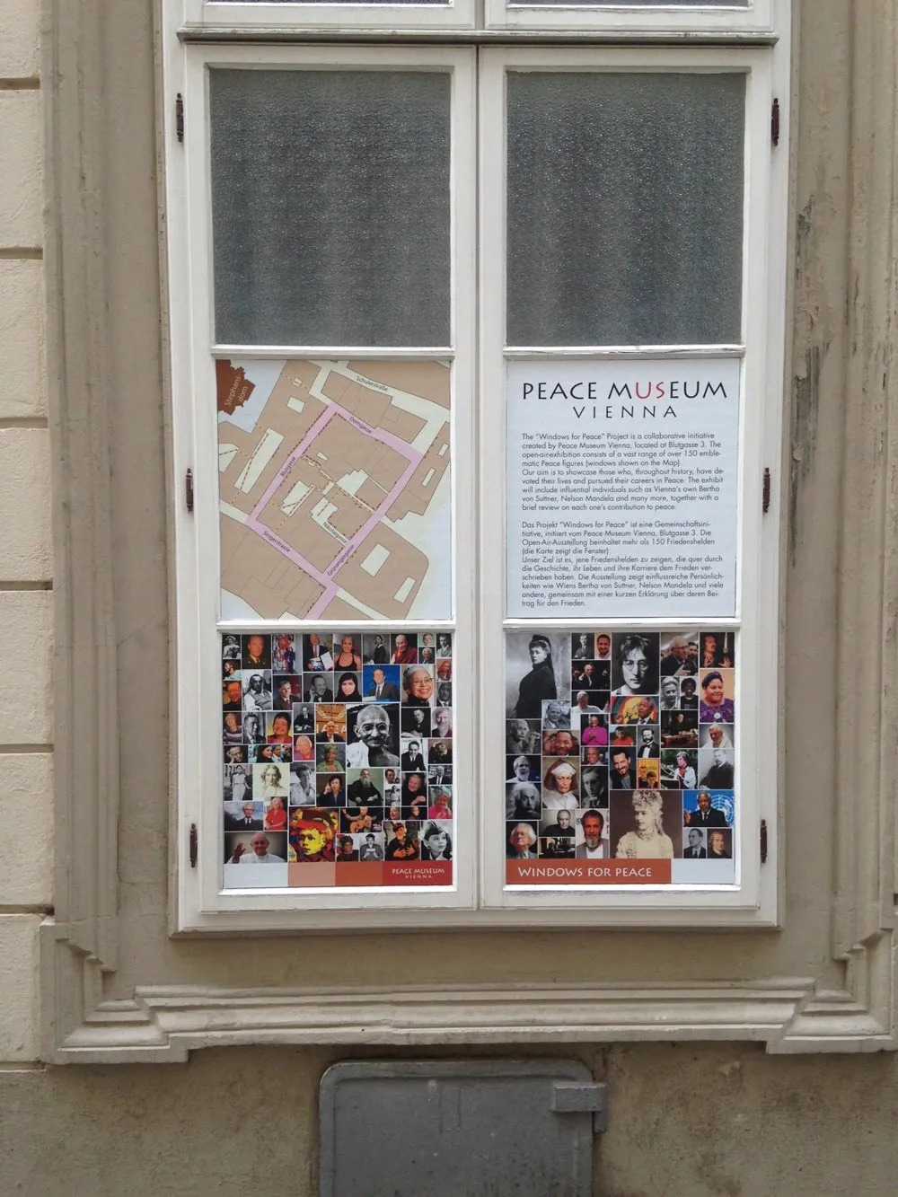 Vitrine met de tekst 'Peace Museum Vienna', een kaart en een collage van portretten op een gebouwgevel