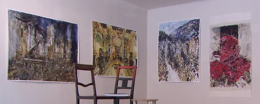 Cuatro grandes pinturas abstractas cuelgan de las paredes blancas de una sala de galería, con dos sillas de madera colocadas en el centro.