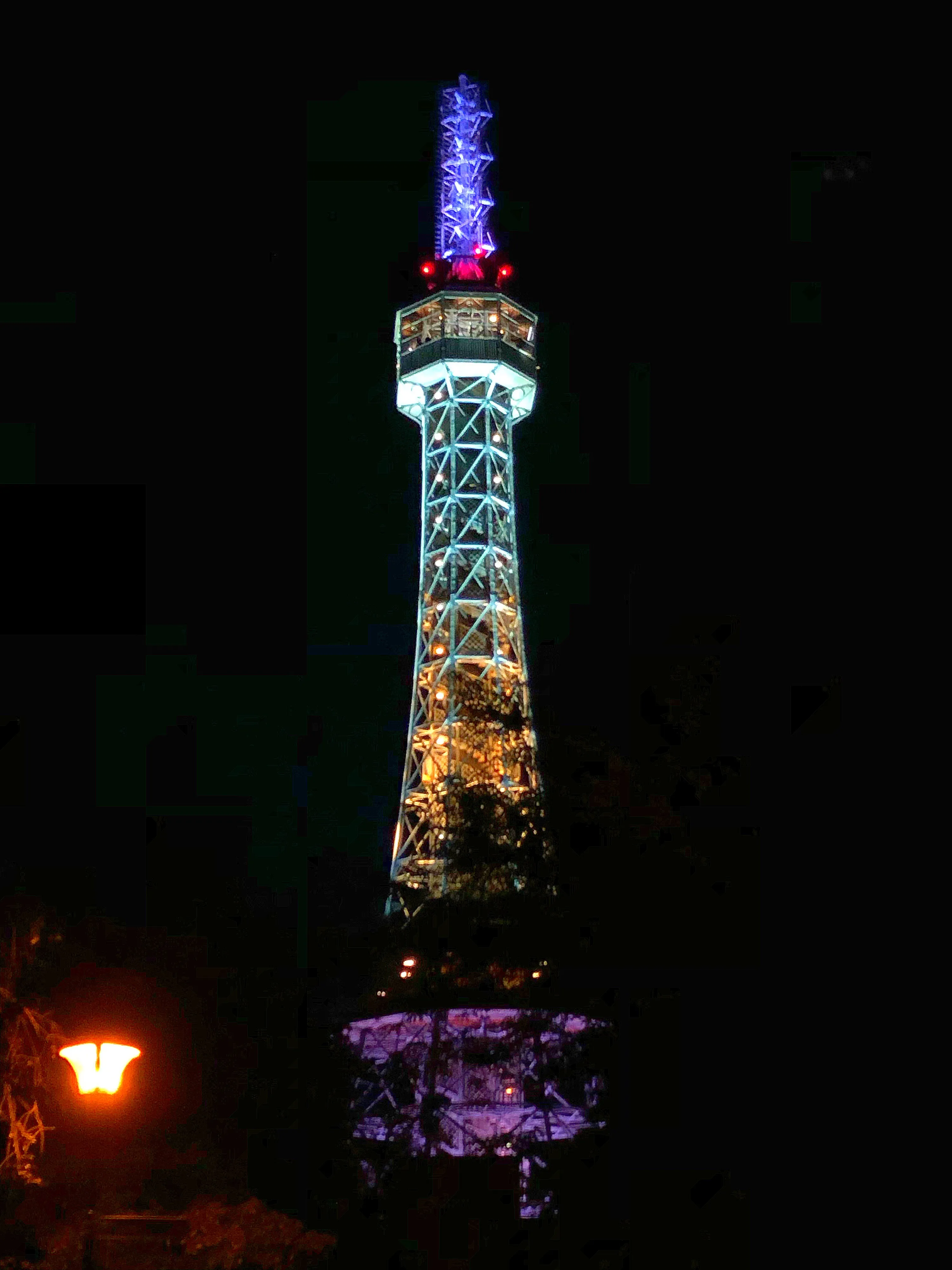 Petřín uitkijktoren verlicht met paarse en blauwe lichten 's nachts