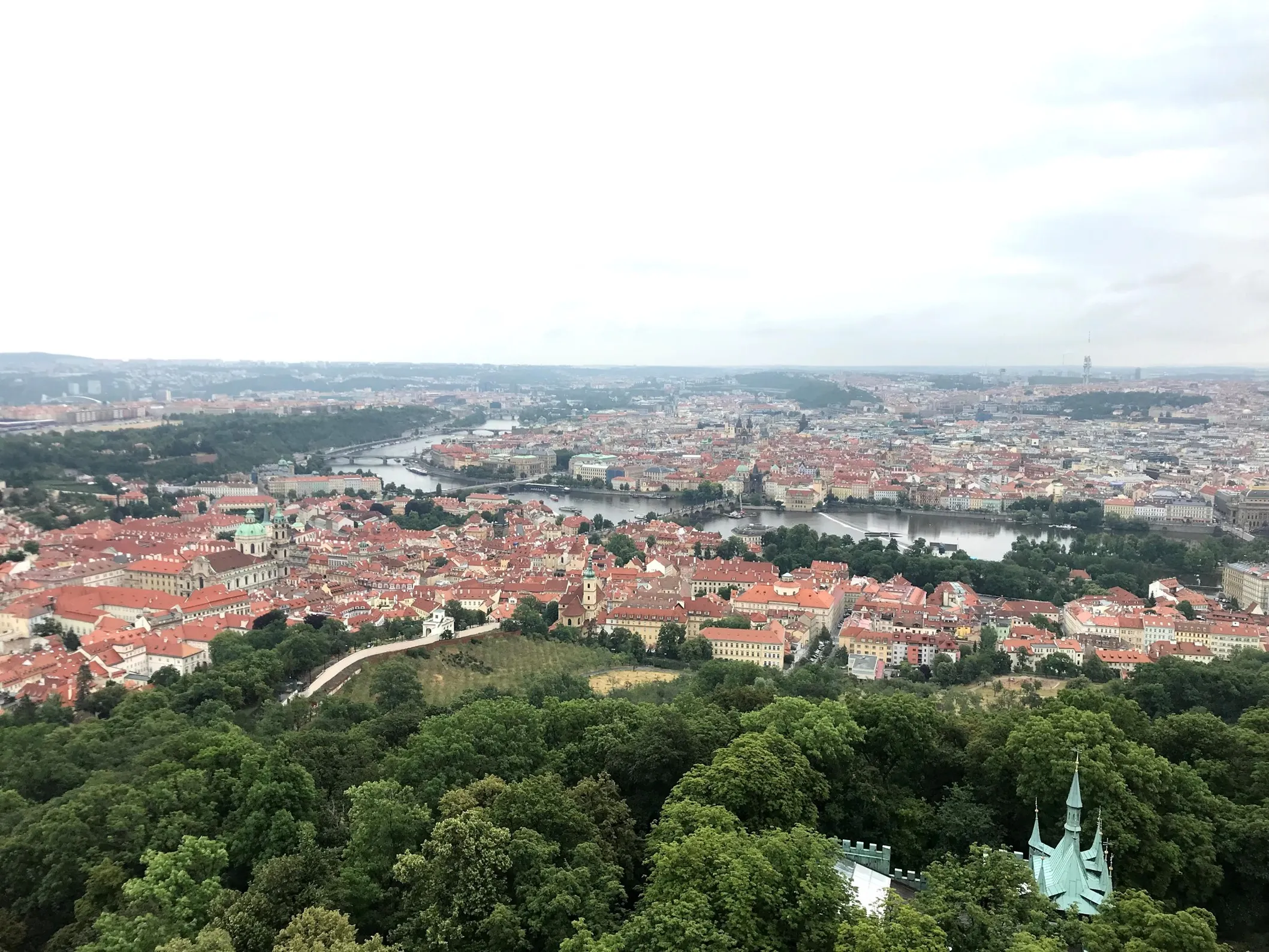 panoramisch uitzicht op Praag vanaf de Petřín-uitkijktoren met rode daken en rivier