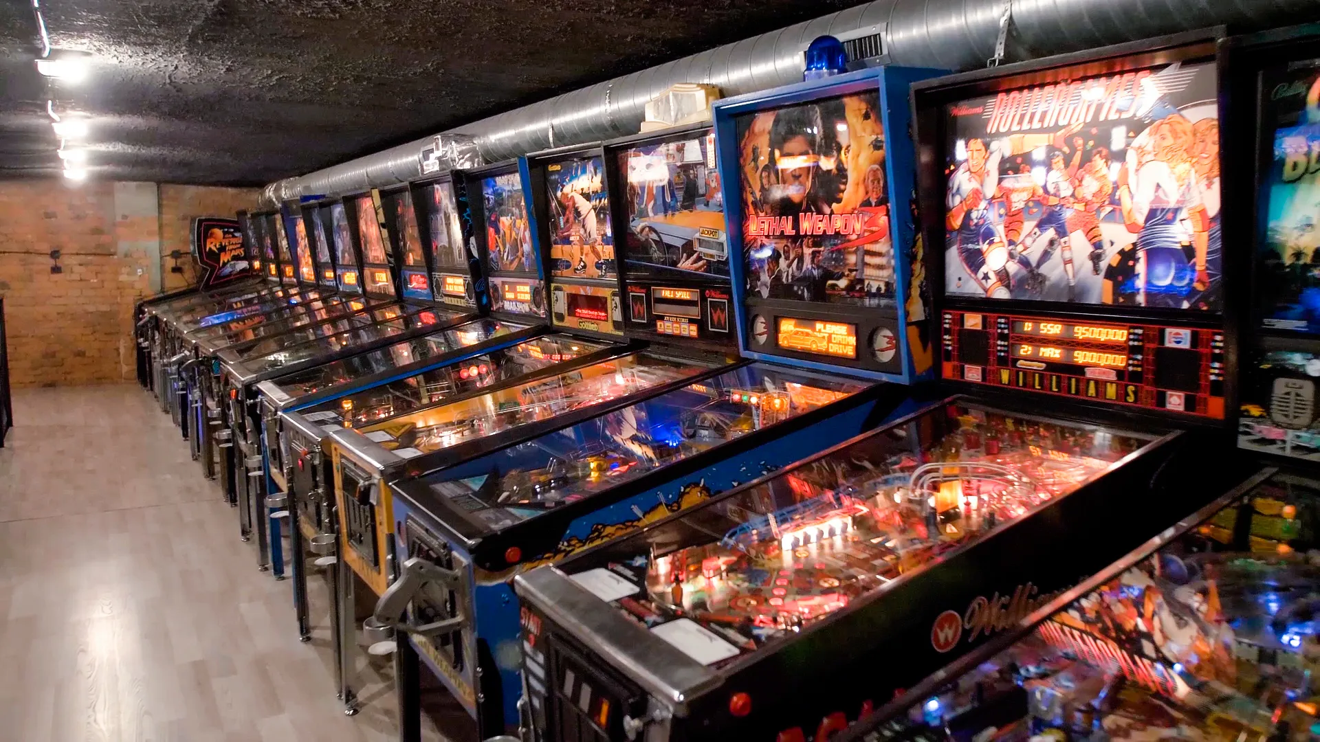 A row of vintage pinball machines with glowing displays and colorful artwork in an arcade room