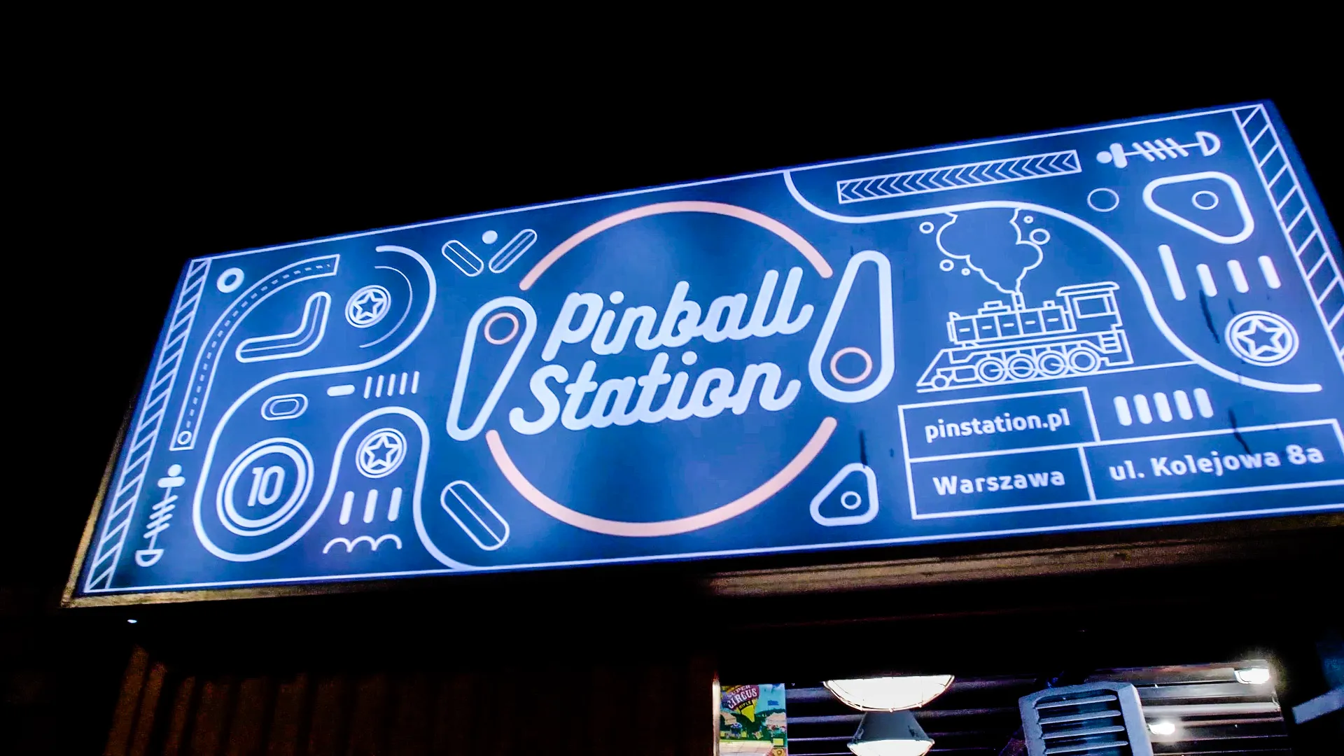 Blue illuminated sign for Pinball Station with white text and pinball-themed graphics