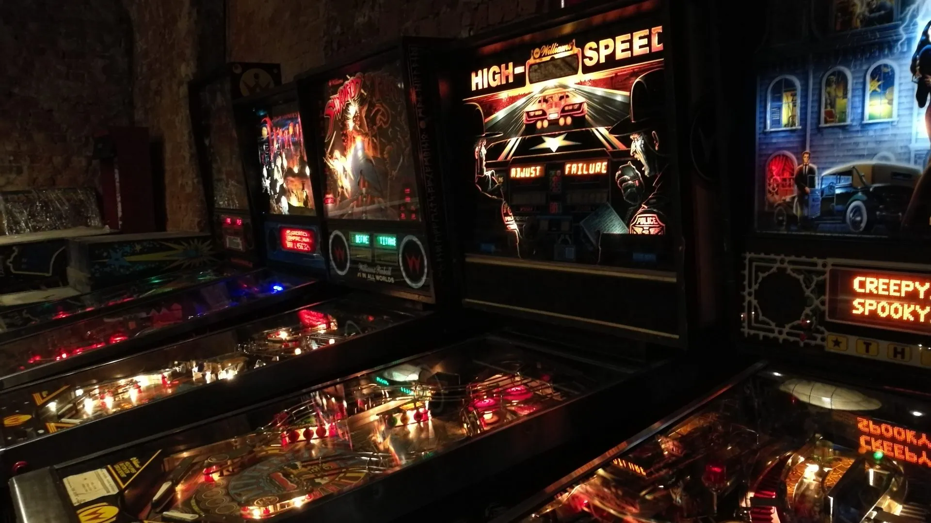 lit pinball machines with colorful displays and flashing lights in a dark room