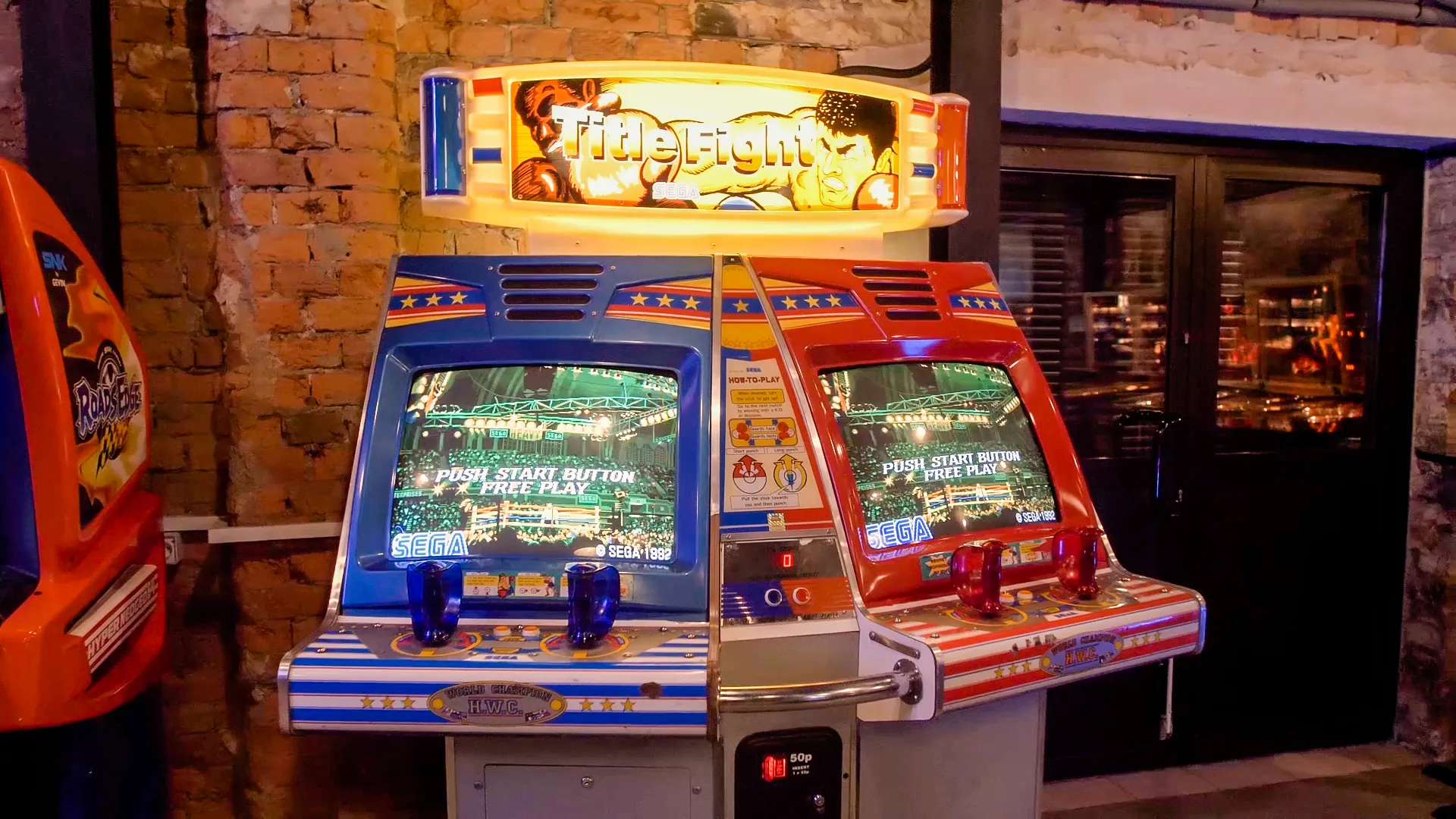 Two retro arcade machines with illuminated screens and colorful cabinets, one labeled 'Final Fight', set against a brick wall