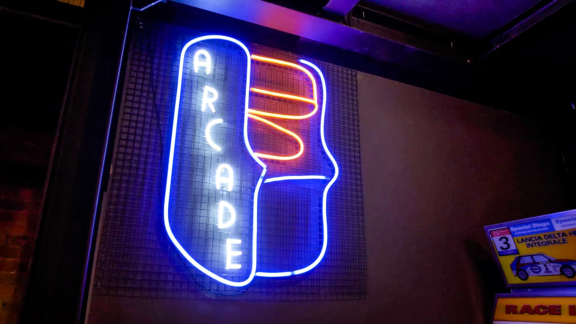 Neon sign with the word 'ARCADE' in blue and an outline of a pinball machine in orange and blue