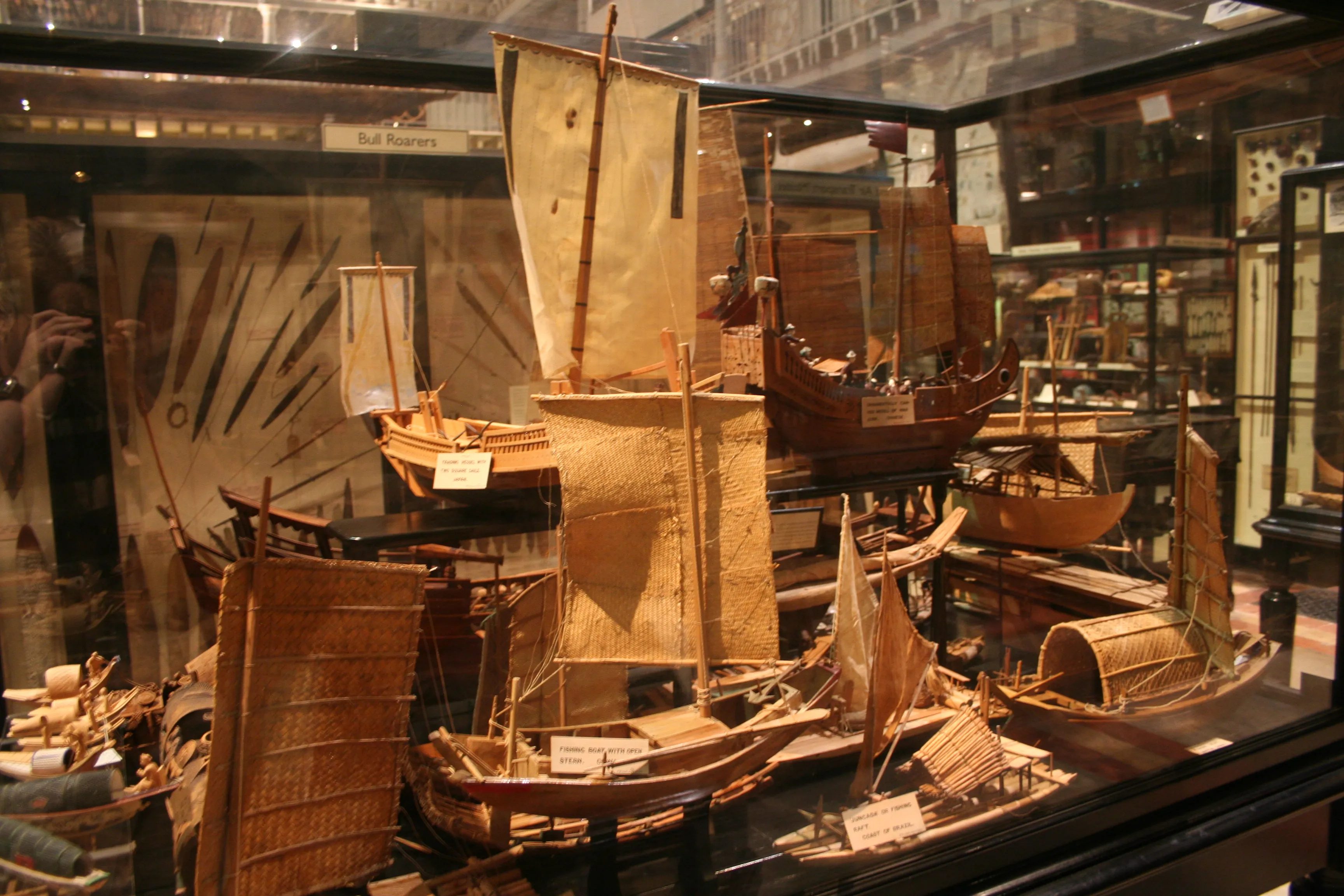 Szklana gablota wypełniona tradycyjnymi modelami łodzi i jednostek pływających z tkanymi żaglami w Pitt Rivers Museum