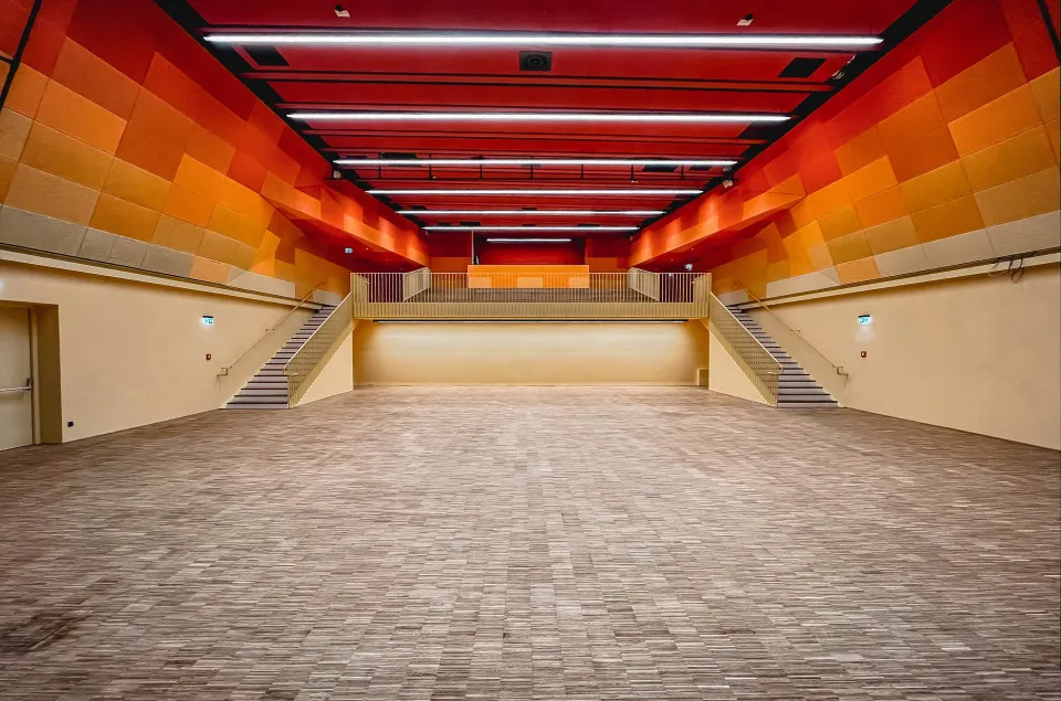 Ruime hal met rode en oranje geometrische plafondpanelen en trappen aan beide zijden