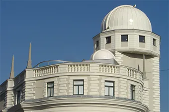 Witte koepel en façade van Planetarium Wien tegen een blauwe hemel