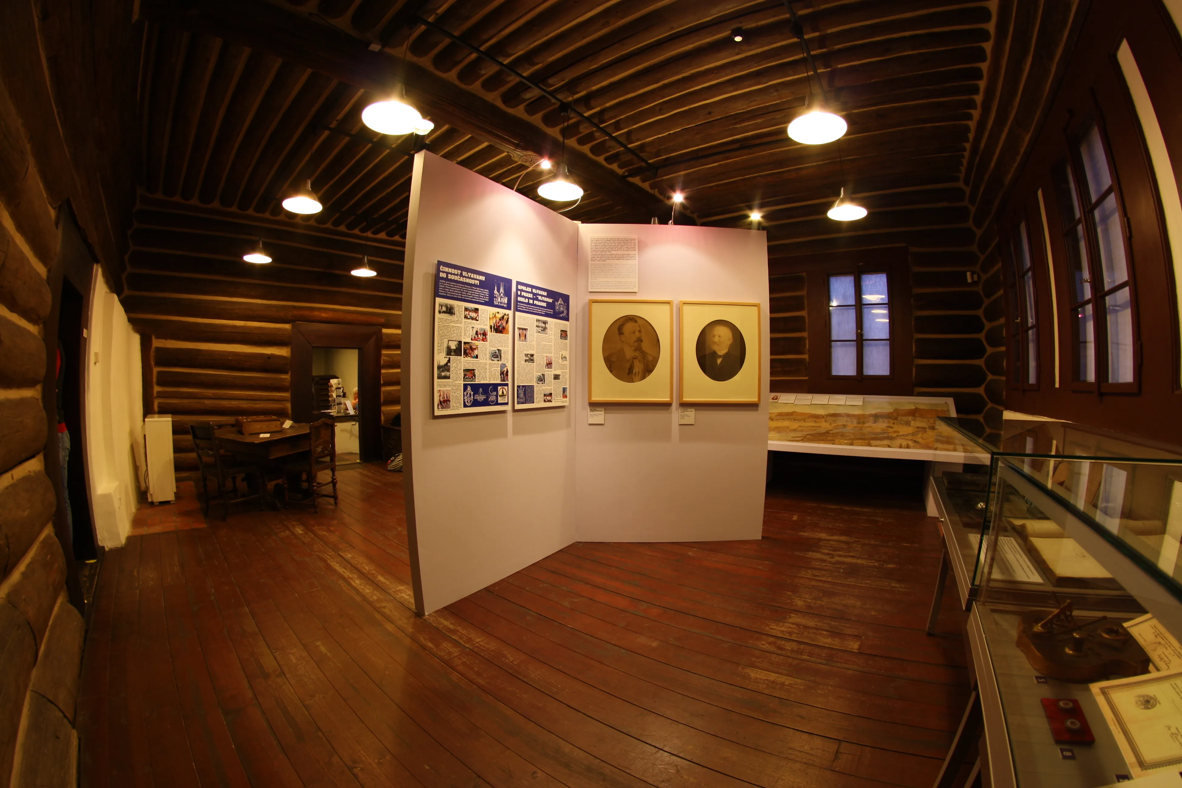 houten interieur met tentoonstellingspanelen en ingelijste portretten