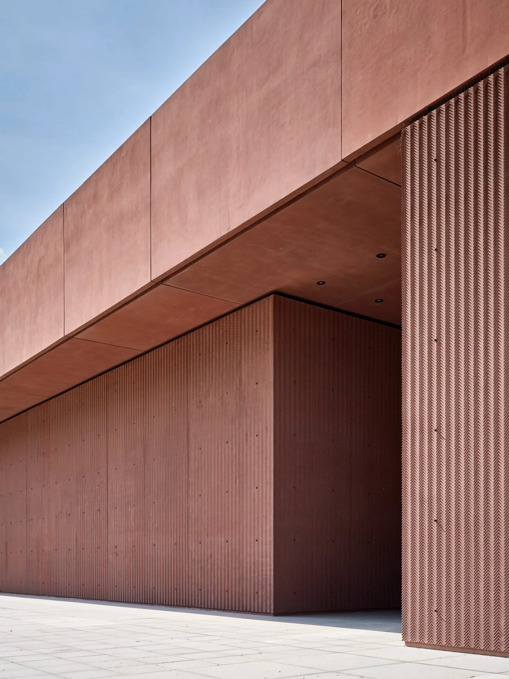 modern gebouw met een roze betonnen buitenkant en verticale geribbelde panelen