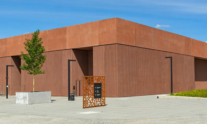 modern gebouw met een roodbruine gevel en een kleine boom ervoor