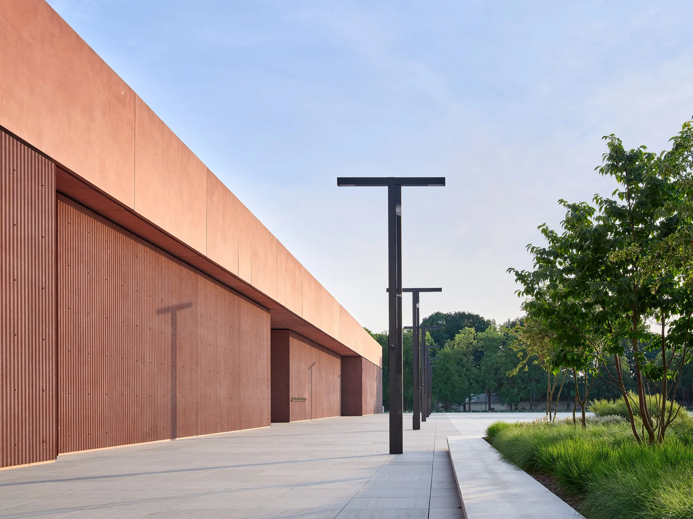 modern gebouw met roze betonnen gevel en zwarte lantaarnpalen