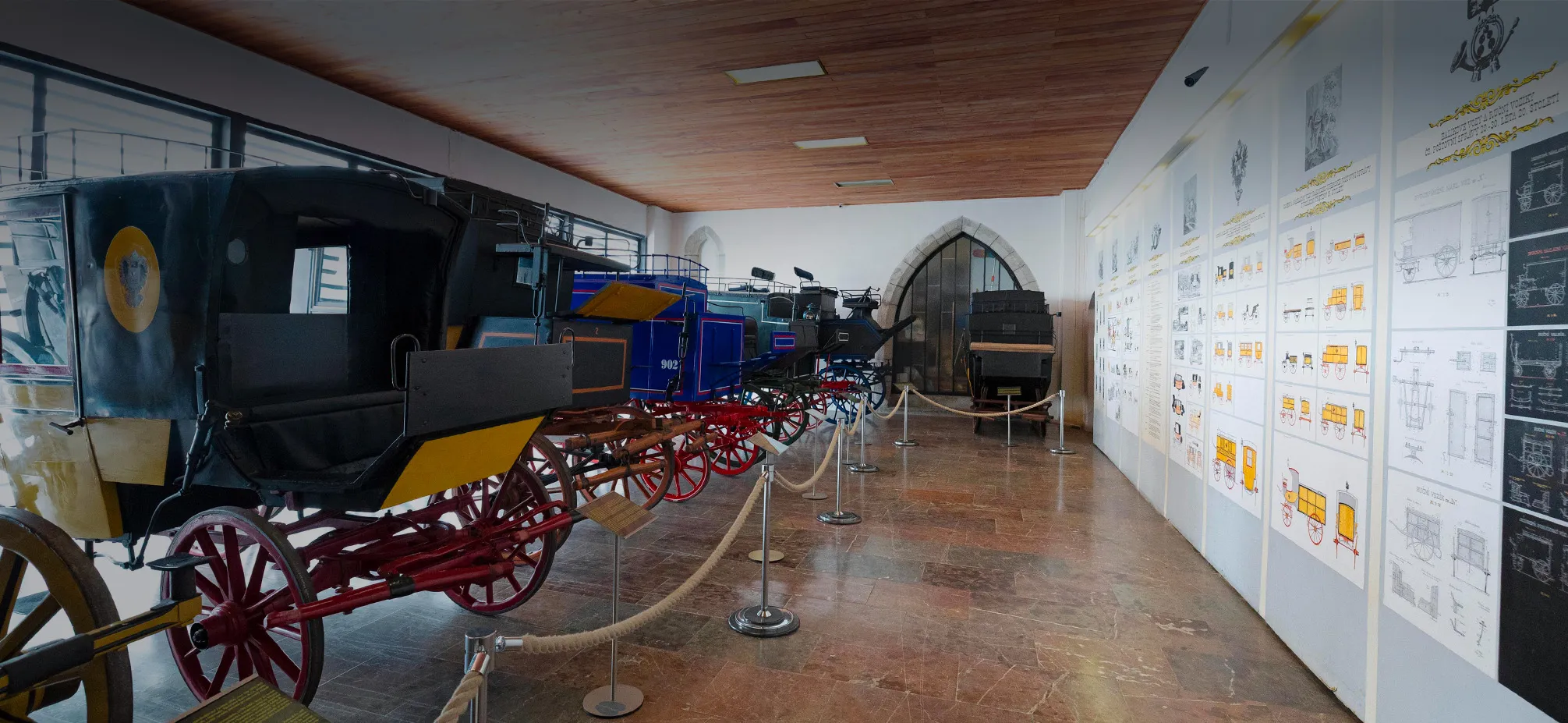 Historic postal carriages on display in a museum gallery with informational panels on the walls
