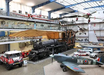 Interior of the Postal Museum with a steam locomotive, vintage car, and airplane on display