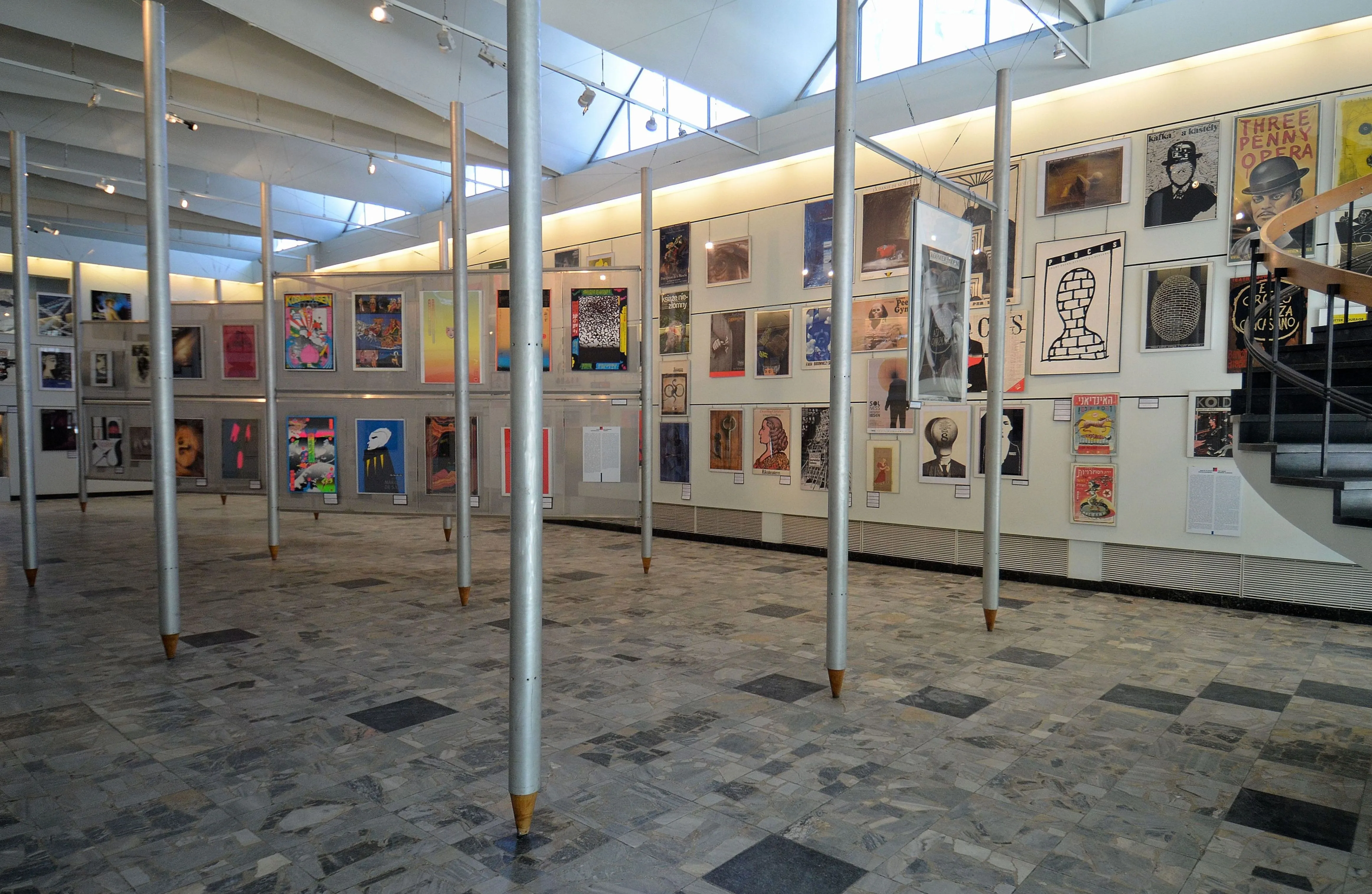 Gallery with posters on walls, white columns, and a patterned floor