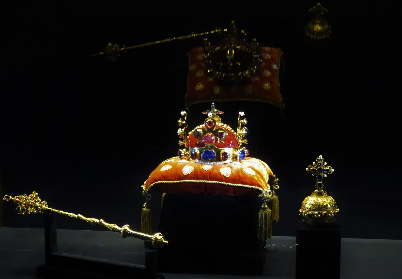 Crown jewels displayed on a red cushion with a scepter and orb nearby