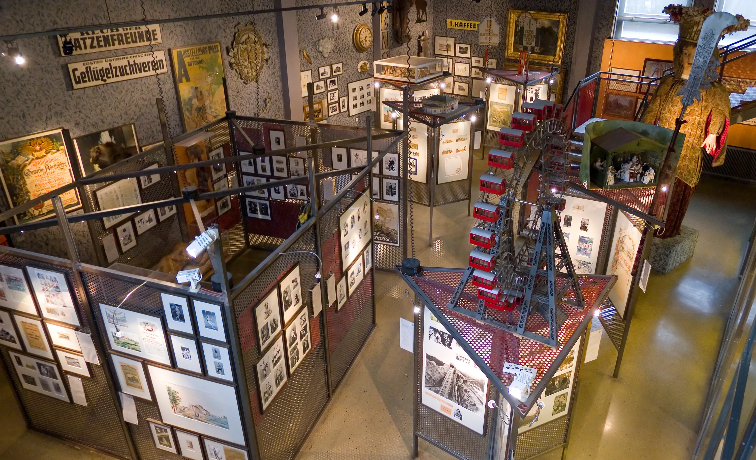 Wnętrze Pratermuseum z gablotami, oprawionymi obrazami i czerwono-białym modelem karuzeli