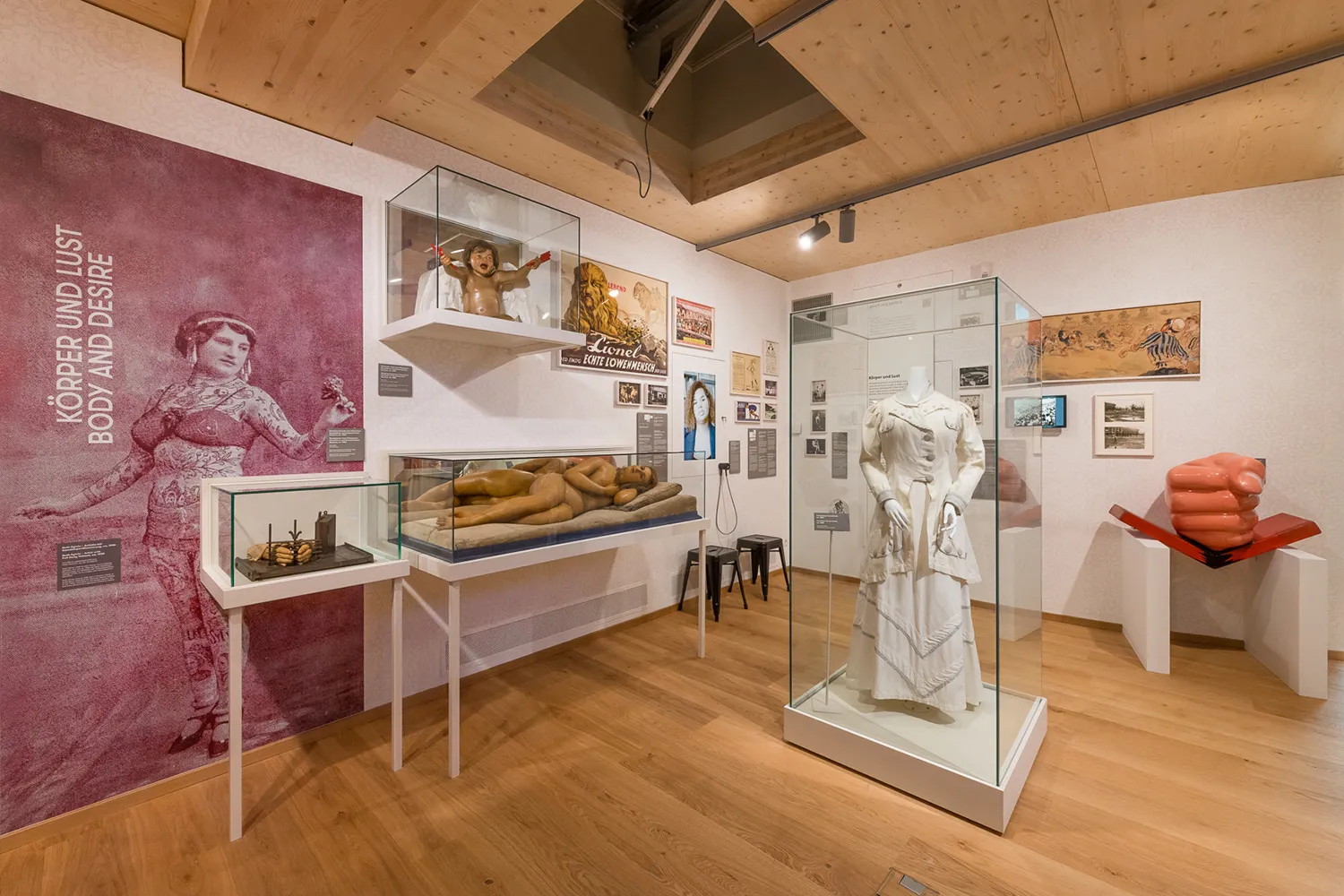 wnętrze muzeum z gablotami, białym posągiem i różową malowidłem ściennym