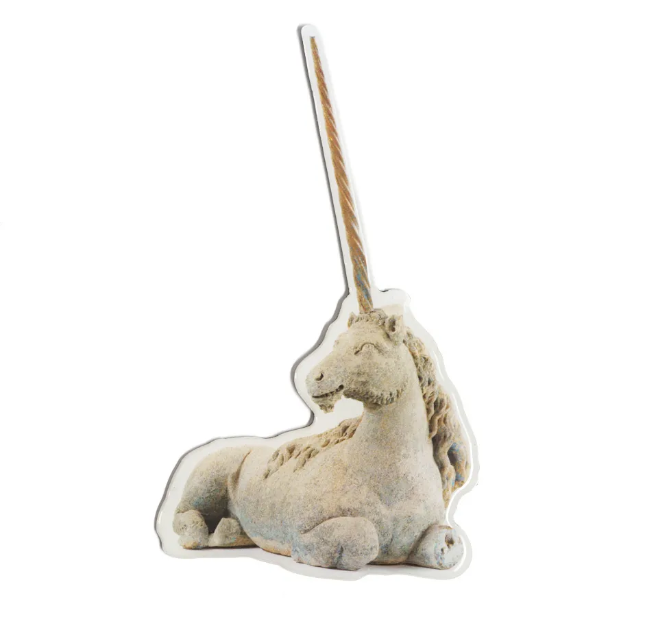 A light-colored unicorn figurine with a long, spiraled horn sitting on a plain surface