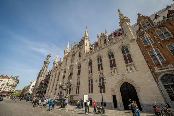 Vista de gran angular de la fachada neogótica del Palacio Provincial en Brujas con visitantes caminando por la plaza