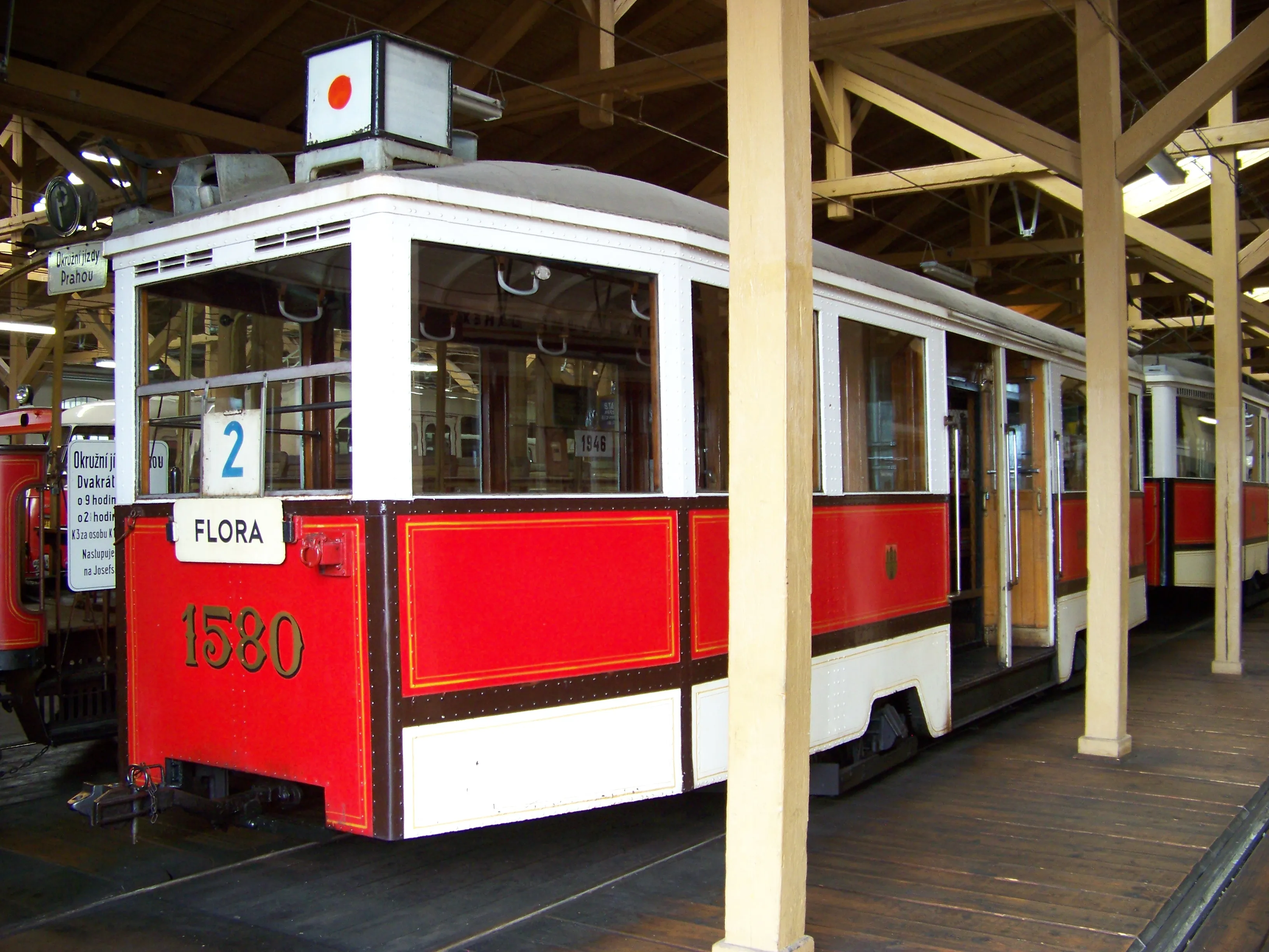 A red and white tram numbered 1580 with 'FLORA' written on the front, displayed indoors under a wooden roof structure.