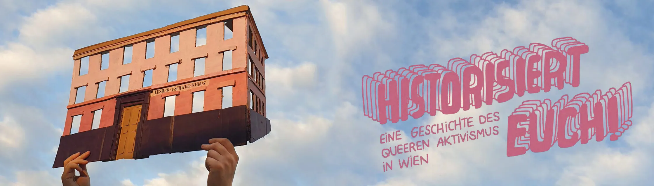 Dłoń trzyma model budynku ze znakiem z napisem 'HISTORISIERT EUCH!' i 'EINE GESCHICHTE DES QUEEREN AKTIVISMUS IN WIEN' na tle niebieskiego nieba.