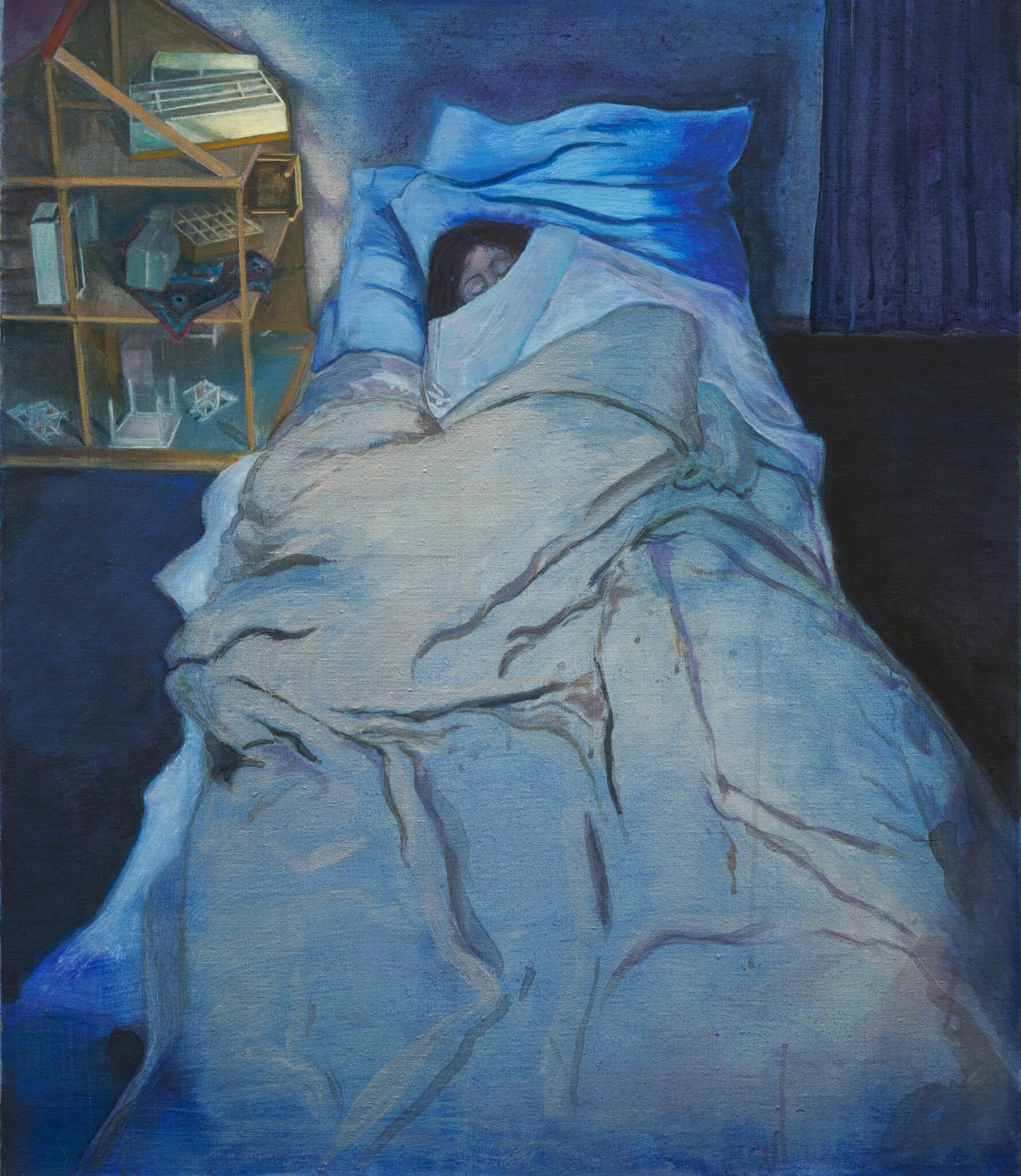 Una persona yace en la cama bajo ropa de cama azul, parcialmente cubierta, con un armario de madera que contiene cristalería y libros visible al fondo.