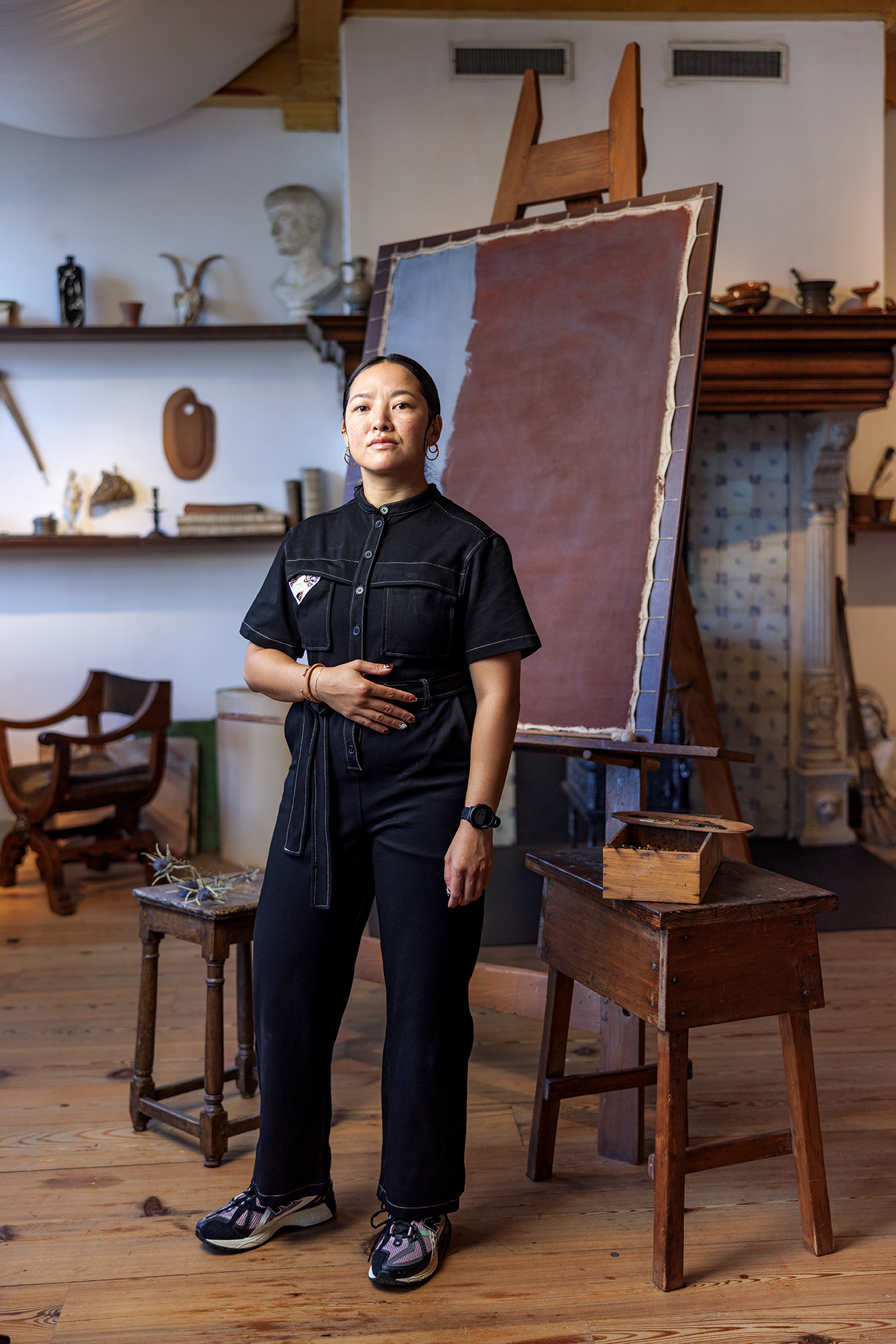 Persona de pie en el estudio reconstruido de Rembrandt con suelo de madera, caballete, muebles de época y materiales de arte en estantes