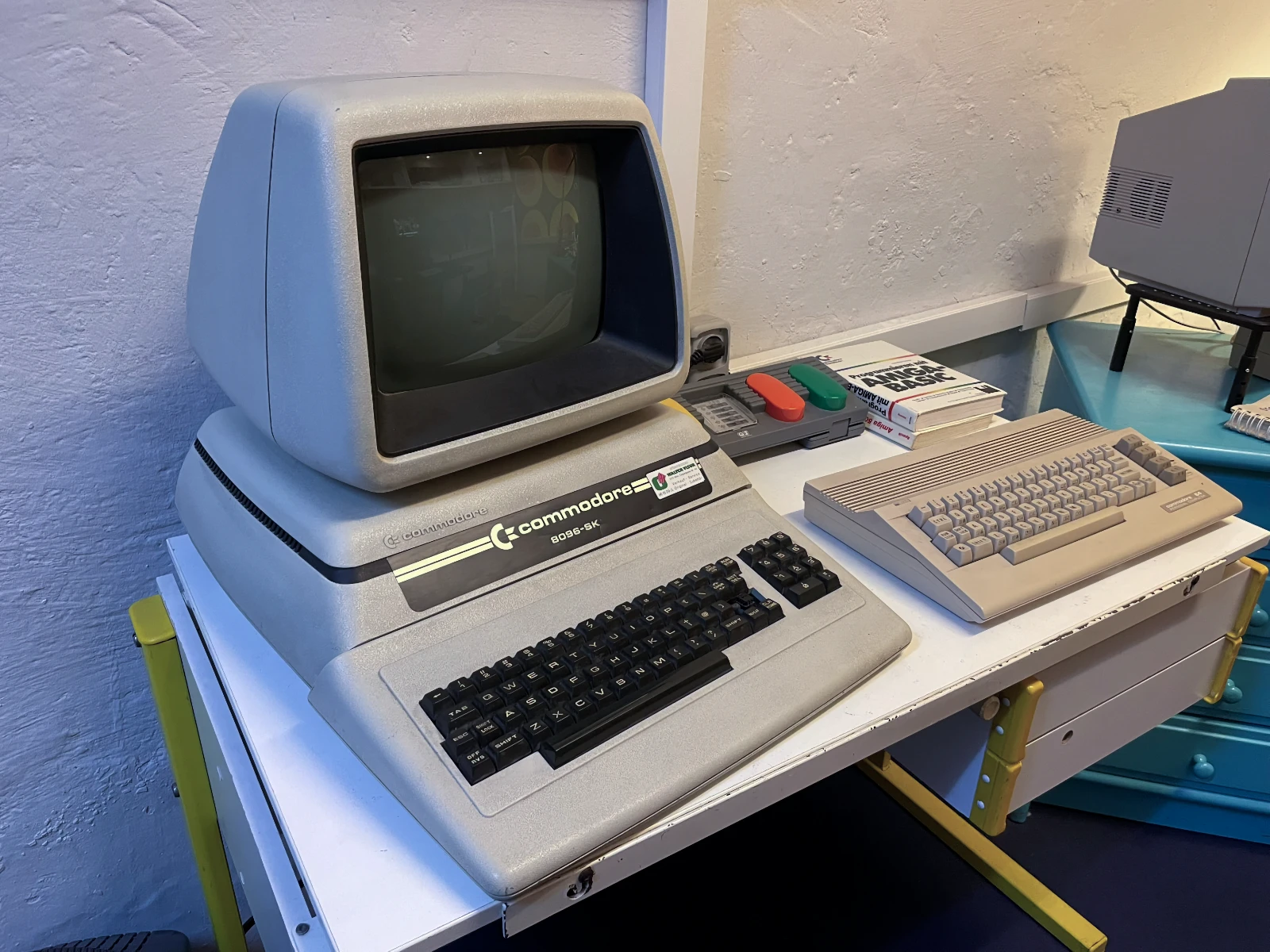 Un ordenador Commodore 64 vintage con monitor y teclado sobre una mesa, junto a un teclado separado y controles de arcade.