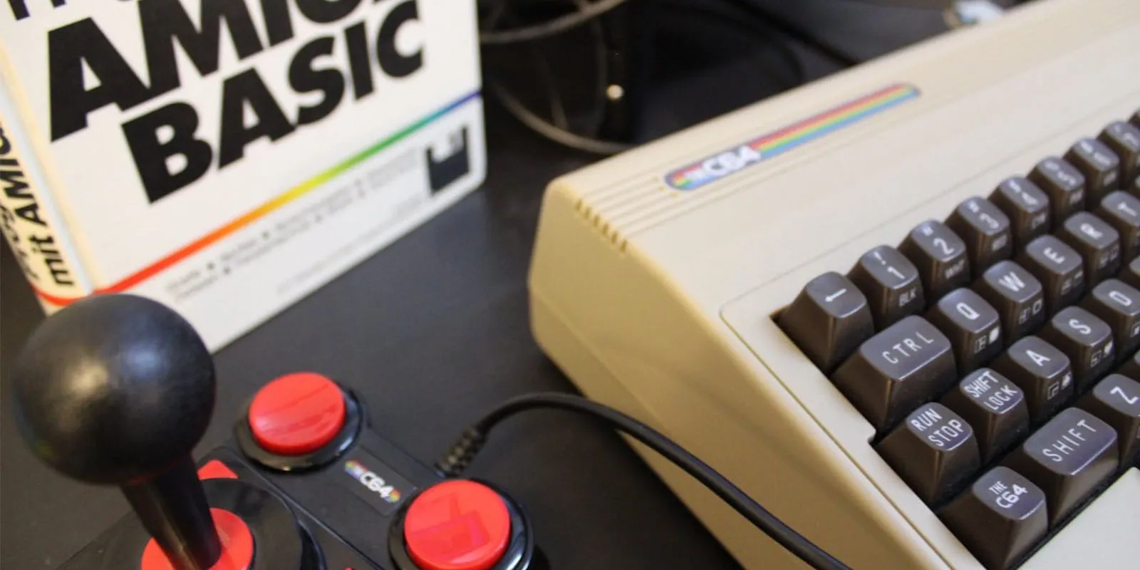 Ordenador Commodore 64 vintage con joystick y un libro titulado 'Amiga Basic'